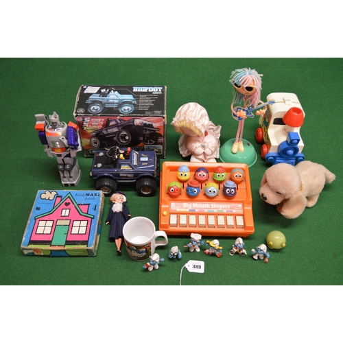 389 - Mixed toy lot to include: boxed Big Foot truck, walking dog, Smurfs, musical doll, 1986 Hasbro Trans... 