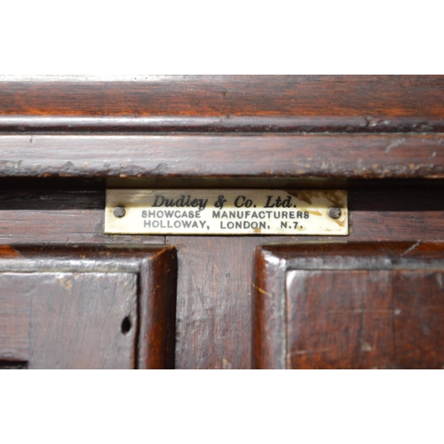 26 - Dudley & Co. mahogany stained haberdashery cabinet having sixteen glazed drawers over two sliding do... 