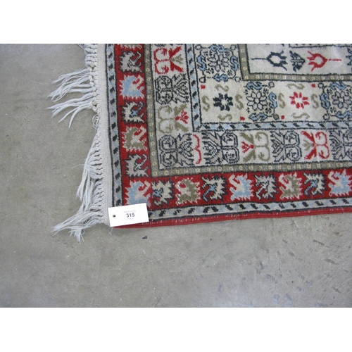 315 - Patterned rug on a red and cream ground with tassels - 3.10m x 1.97m