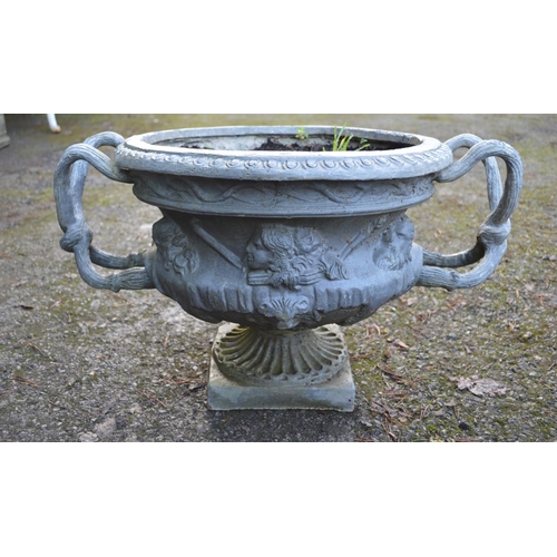 11 - Pair of 20th century lead garden urns the bowls decorated with faces and having root formed handles,... 