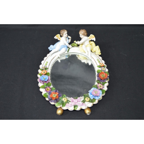 216 - Sitzendorf floral decorated free standing oval mirror mounted with two cherubs - 11.25