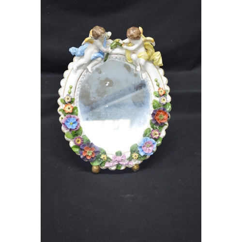 216 - Sitzendorf floral decorated free standing oval mirror mounted with two cherubs - 11.25