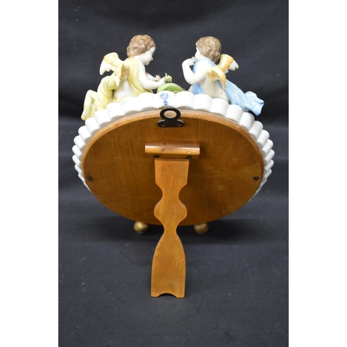 216 - Sitzendorf floral decorated free standing oval mirror mounted with two cherubs - 11.25