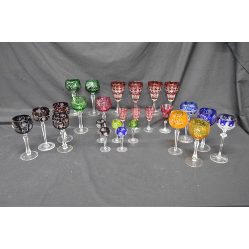 228 - Group of twenty six various cut crystal and glass coloured overlay glasses with clear stems, on circ... 