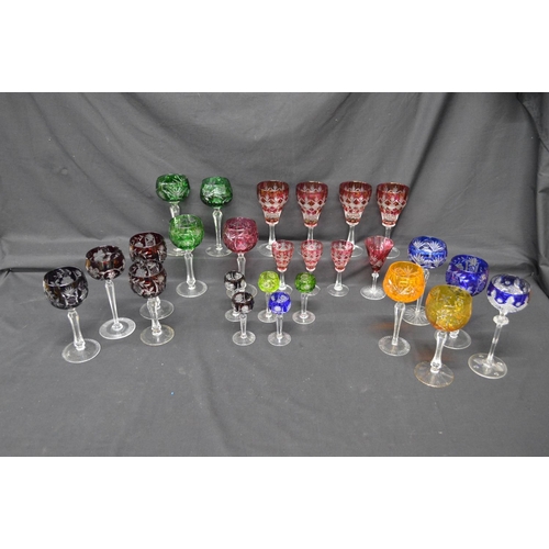 228 - Group of twenty six various cut crystal and glass coloured overlay glasses with clear stems, on circ... 