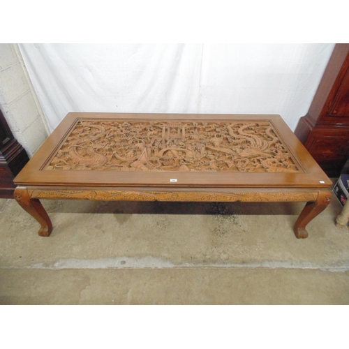 508 - Large deeply carved hardwood coffee table with glass top cover, the rectangular top having a scene w... 