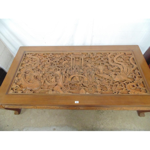 508 - Large deeply carved hardwood coffee table with glass top cover, the rectangular top having a scene w... 