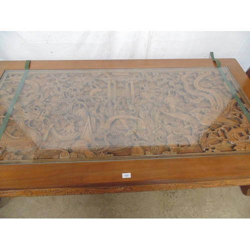 508 - Large deeply carved hardwood coffee table with glass top cover, the rectangular top having a scene w... 