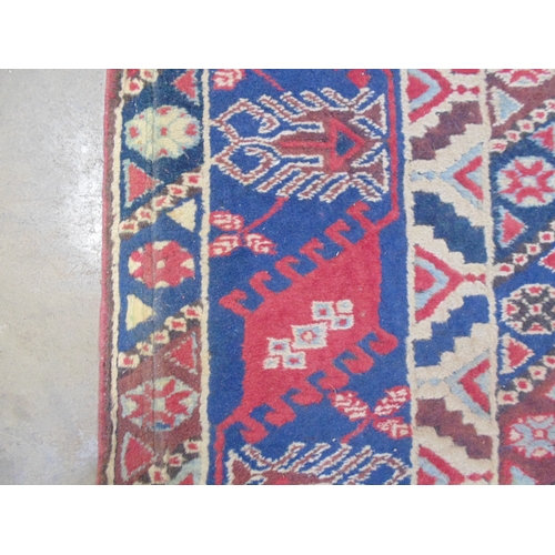 509 - Turkish patterned rug with red and blue ground having three geometric central motifs with a four sec... 