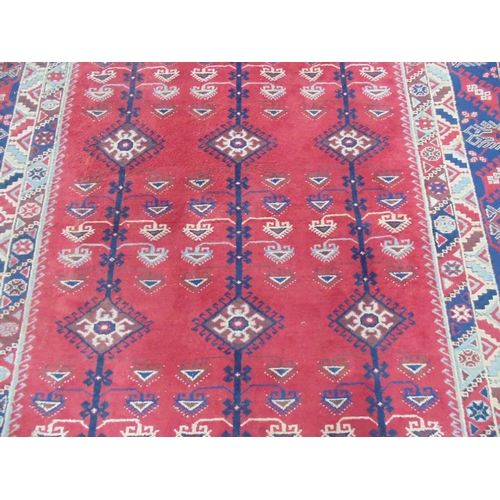 509 - Turkish patterned rug with red and blue ground having three geometric central motifs with a four sec... 