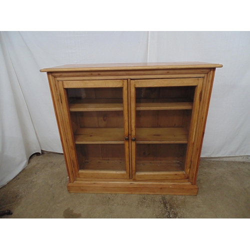 445 - Pine bookcase having two glazed doors opening to two removable shelves, standing on plinth base - 11... 