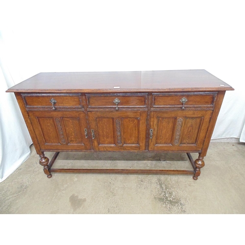 493 - Oak sideboard having three drawers (one baize lined) over three panelled cupboard doors, standing on... 