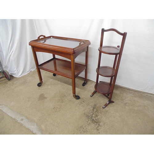 516 - Mahogany and walnut two tier tea trolley having a lift out glass bottom two handled tray, standing o... 