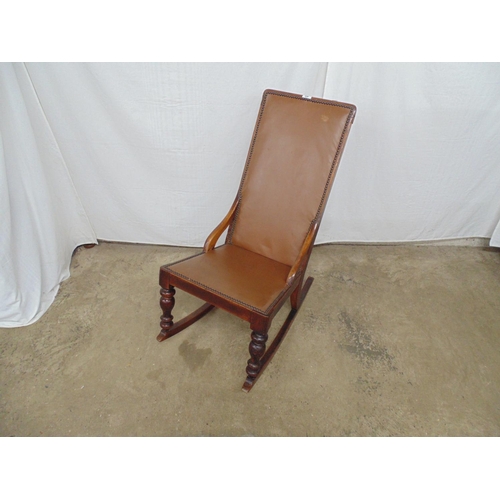 526 - Mahogany framed rocking chair with studded brown leather upholstery, standing on turned front suppor... 