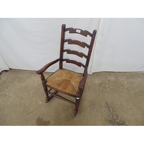 539 - Child's beech ladderback rocking chair having a rush seat and standing on turned legs - 42.5cm x 54c... 