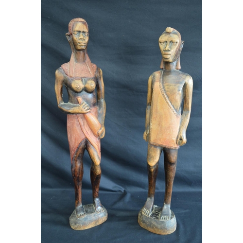 95 - Two hardwood carved figures of tribal people standing on shaped oval bases - 63cm and 60.5cm tall