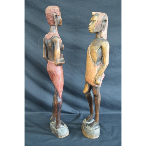 95 - Two hardwood carved figures of tribal people standing on shaped oval bases - 63cm and 60.5cm tall