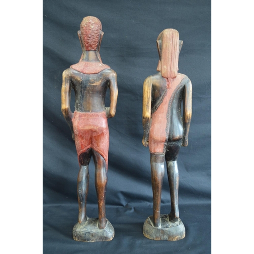 95 - Two hardwood carved figures of tribal people standing on shaped oval bases - 63cm and 60.5cm tall