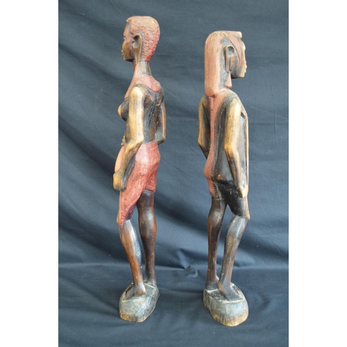 95 - Two hardwood carved figures of tribal people standing on shaped oval bases - 63cm and 60.5cm tall
