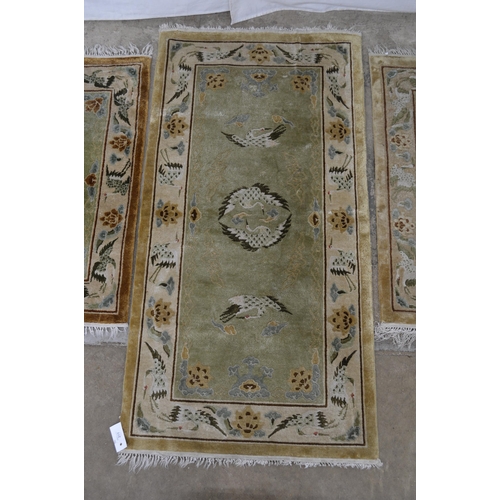 277 - Group of three patterned rugs all having a central panel and border decorated with storks and flower... 