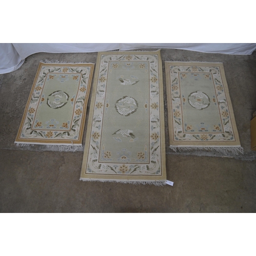 277 - Group of three patterned rugs all having a central panel and border decorated with storks and flower... 