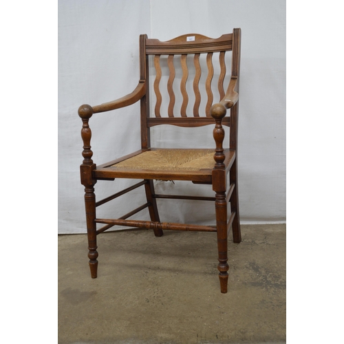 281 - Mahogany Arts & Crafts elbow chair having a slatted back, rush seat and arm rests terminating with s... 