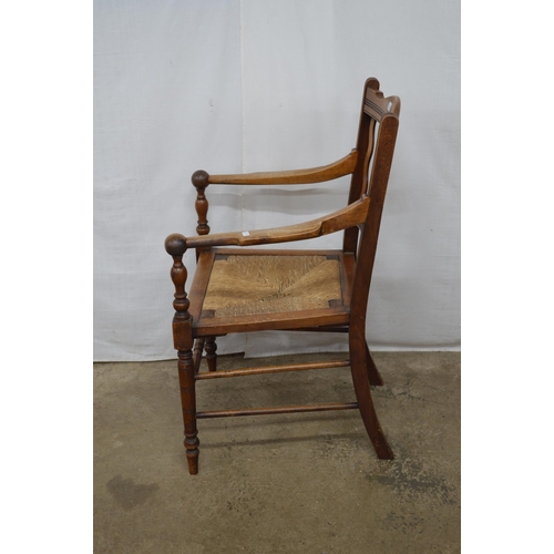 281 - Mahogany Arts & Crafts elbow chair having a slatted back, rush seat and arm rests terminating with s... 