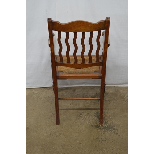 281 - Mahogany Arts & Crafts elbow chair having a slatted back, rush seat and arm rests terminating with s... 