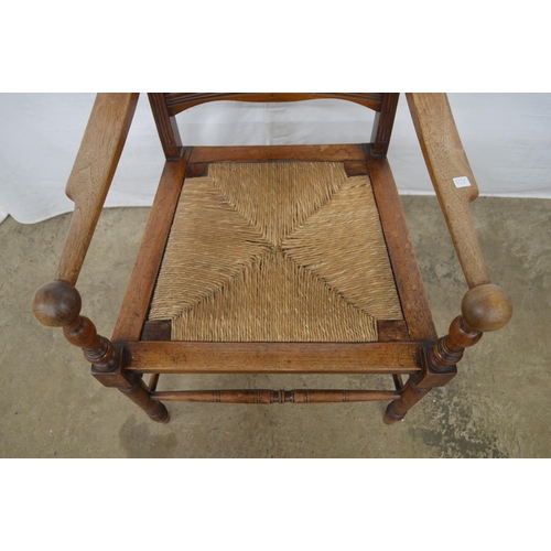 281 - Mahogany Arts & Crafts elbow chair having a slatted back, rush seat and arm rests terminating with s... 