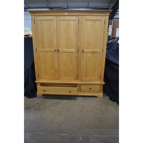 289 - Modern oak triple wardrobe, the top section having three panelled doors, two doors opening to a hang... 