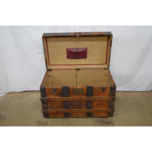 334 - Wooden metal bound dome top trunk, the hinged lift top lid opening to a canvas lined interior, stand... 