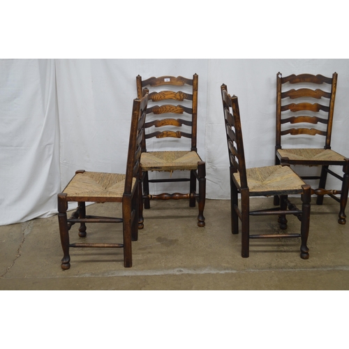 369 - Set of four oak ladderback chairs having rush seats, standing on turned front legs with stretchers -... 