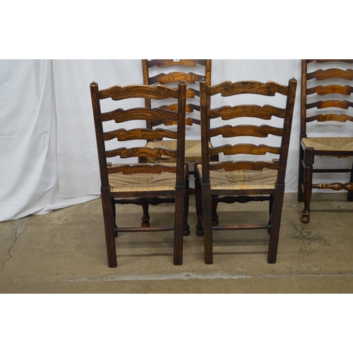 369 - Set of four oak ladderback chairs having rush seats, standing on turned front legs with stretchers -... 