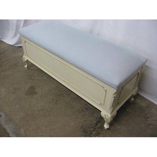 394 - Cream and gilt blanket box having a hinged lift top lid with upholstered padded seat, standing on ca... 