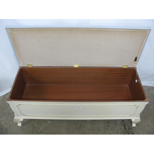 394 - Cream and gilt blanket box having a hinged lift top lid with upholstered padded seat, standing on ca... 