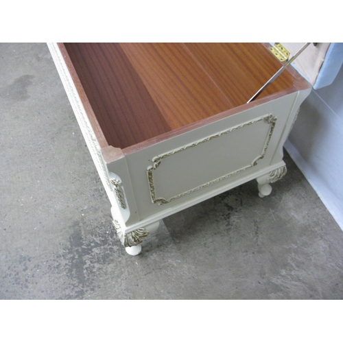 394 - Cream and gilt blanket box having a hinged lift top lid with upholstered padded seat, standing on ca... 