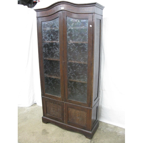 403 - Glazed oak bookcase, the arched pediment top over two frosted floral decorated glass doors, the door... 