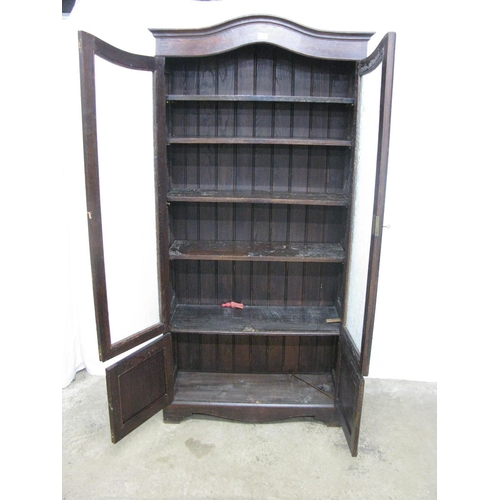 403 - Glazed oak bookcase, the arched pediment top over two frosted floral decorated glass doors, the door... 