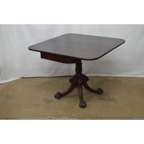 405 - Mahogany fold over tea table with a turned column on four carved splayed supports with paw feet and ... 