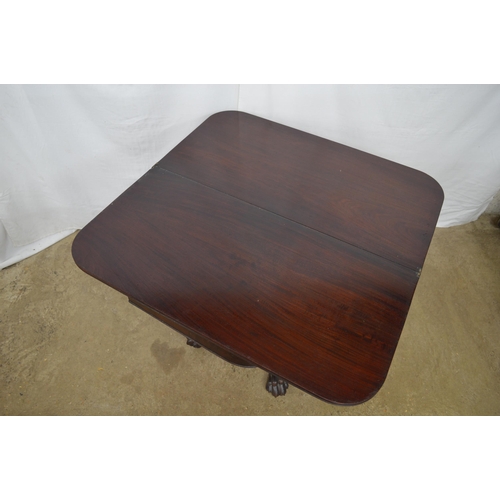 405 - Mahogany fold over tea table with a turned column on four carved splayed supports with paw feet and ... 