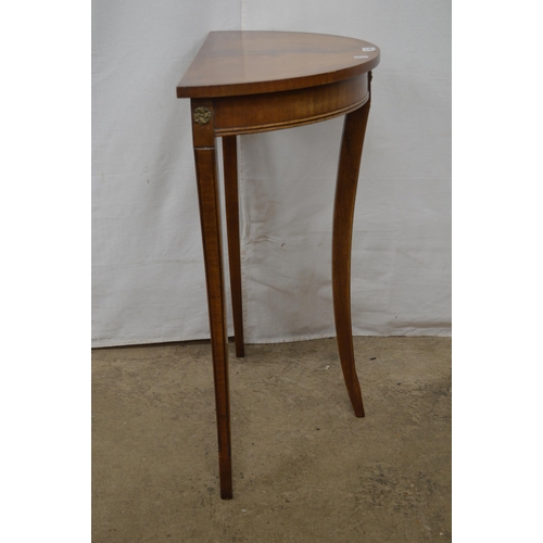 414 - Reproduction cross banded mahogany demi lune side table, standing on shaped tapering legs - 61cm x 3... 