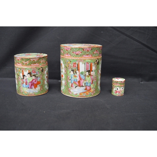 73 - Group of three Famille Rose pattern lidded jars of cylindrical form - tallest 12cm high