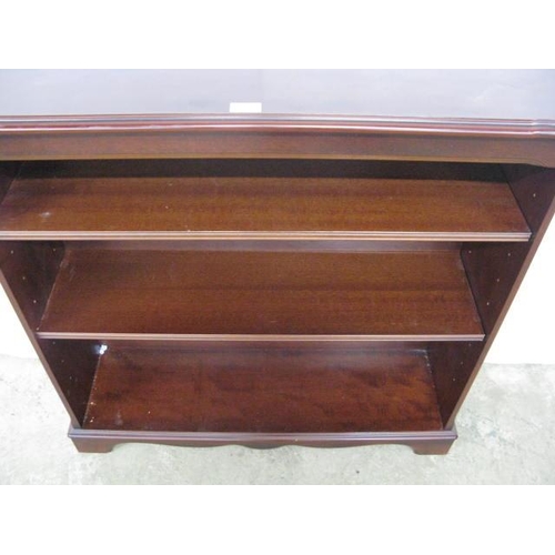 373 - Reproduction mahogany open bookshelves, the shaped top over two adjustable shelves, standing on a pl... 