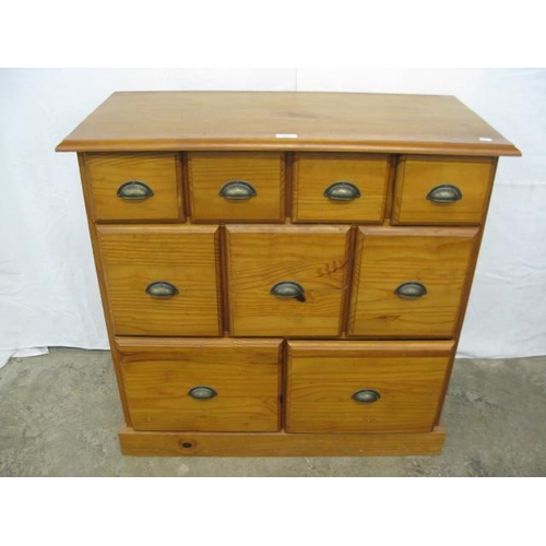 377 - Modern pine chest of drawers having an arrangement of nine graduated drawers with cup handles, stand... 