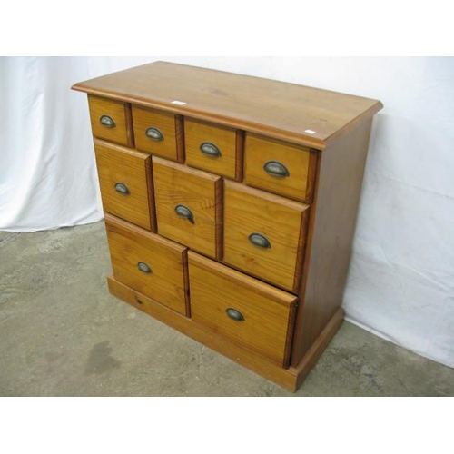 377 - Modern pine chest of drawers having an arrangement of nine graduated drawers with cup handles, stand... 