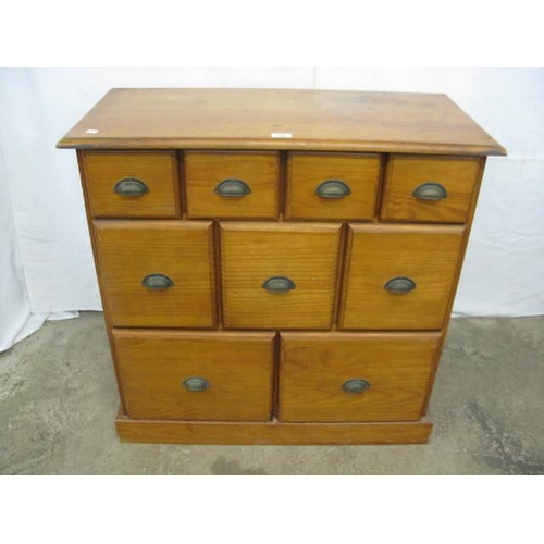 378 - Modern pine chest of drawers having an arrangement of nine graduated drawers with cup handles, stand... 