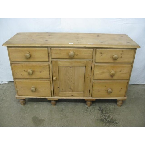 395 - Pine sideboard having a single drawer over a panelled door cupboard flanked by three drawers, standi... 