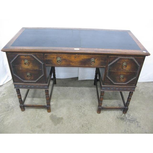 409 - Oak writing desk having an inset leatherette top and an arrangement of five drawers, standing on tur... 