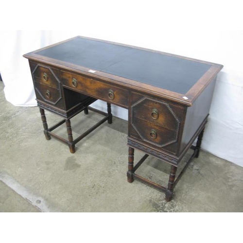 409 - Oak writing desk having an inset leatherette top and an arrangement of five drawers, standing on tur... 