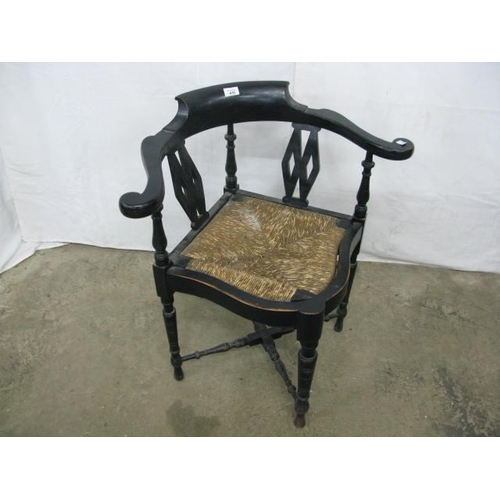 410 - Ebonised corner chair having shaped arms, pierced splats and rush seat, standing on turned legs with... 